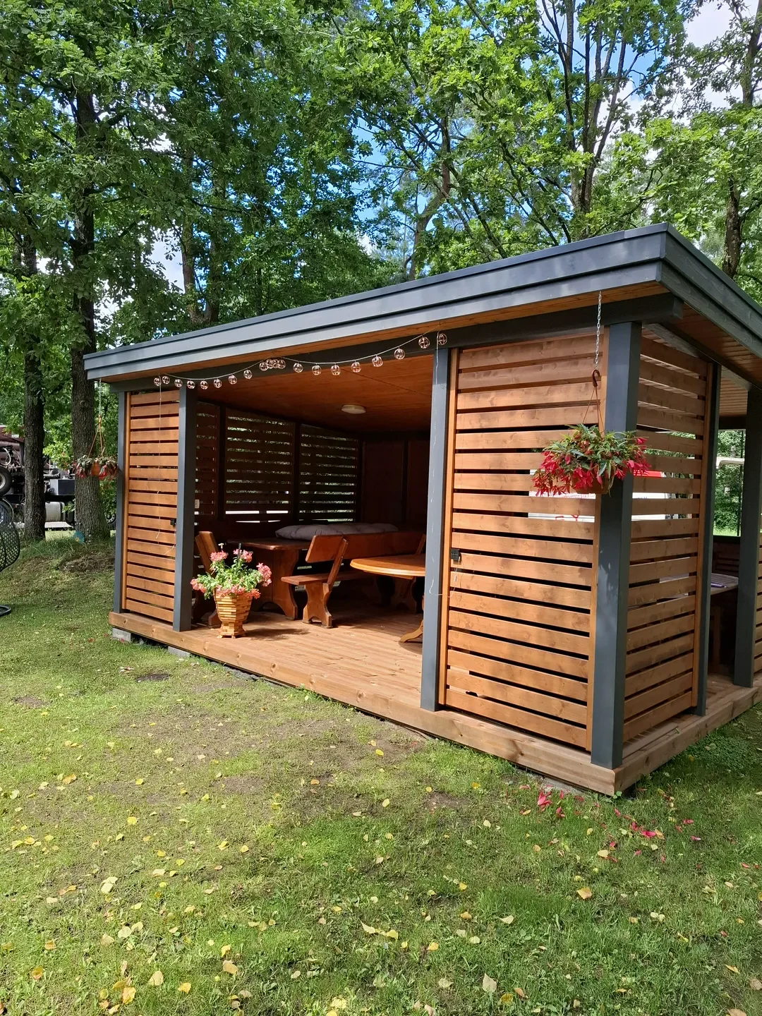 Altany ogrodowe z zabudowaną konstrukcją z drewnianych listew, drewnianą podłogą i meblami