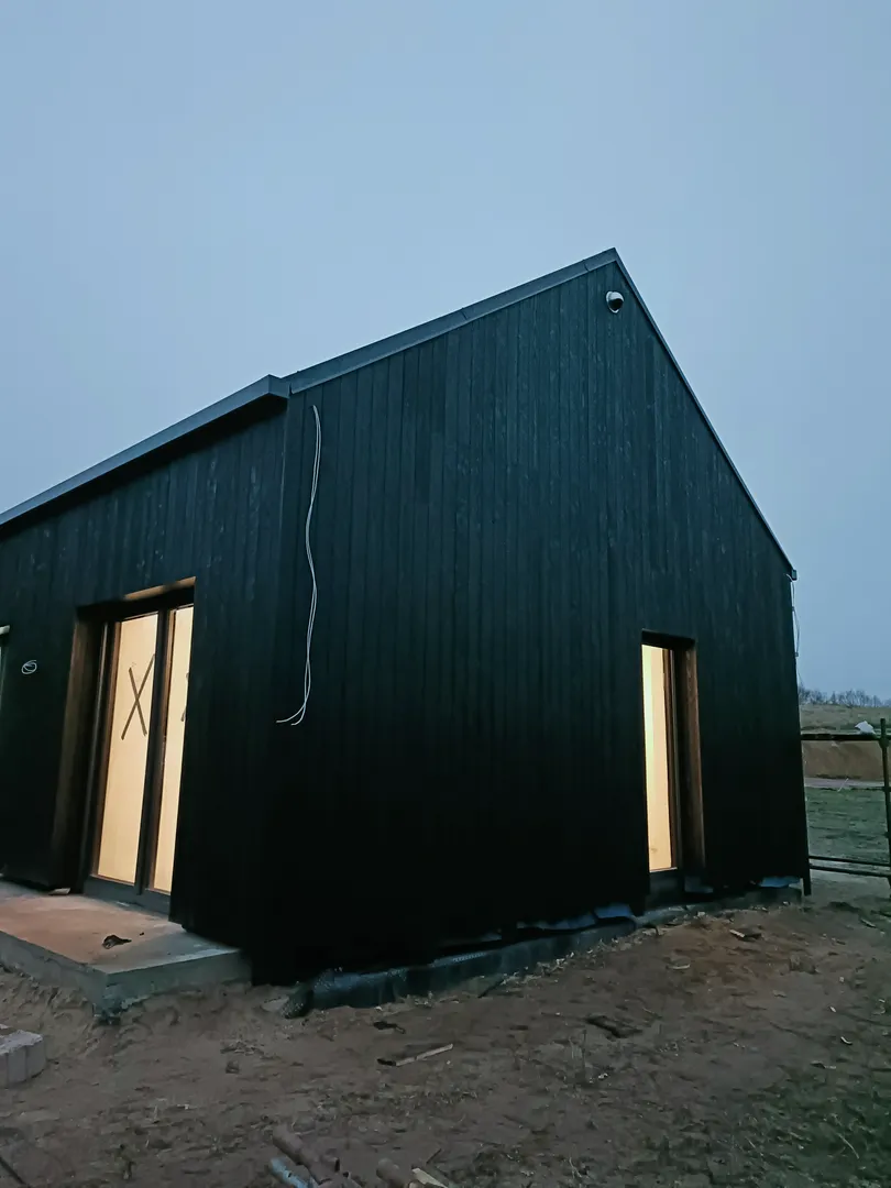 Czarny drewniany domek szkieletowy Domki szkieletowe z przeszkleniami i oświetlonym wnętrzem