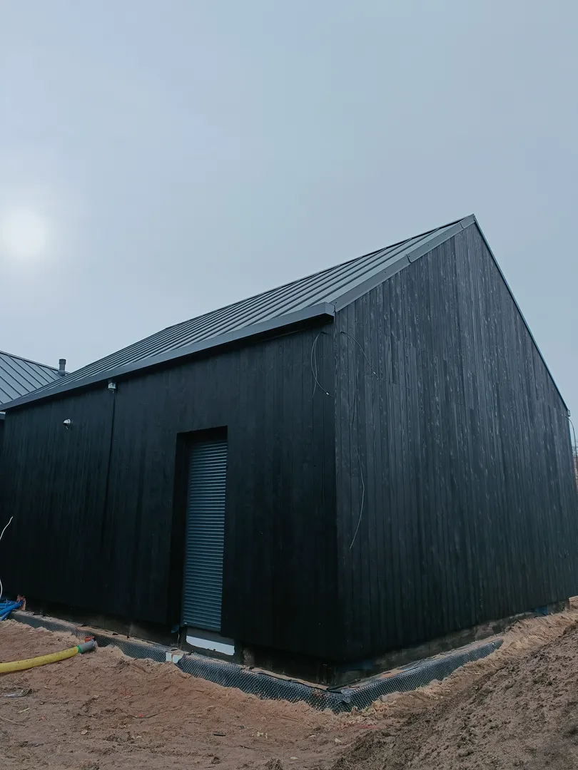 Elewacje drewniane czarną deską modrzewia na budynku w budowie