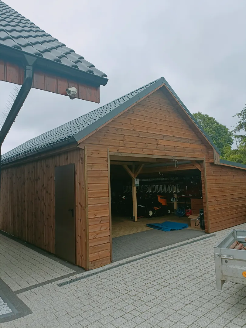 Drewniany carport z otwartą przestrzenią do przechowywania sprzętu ogrodowego