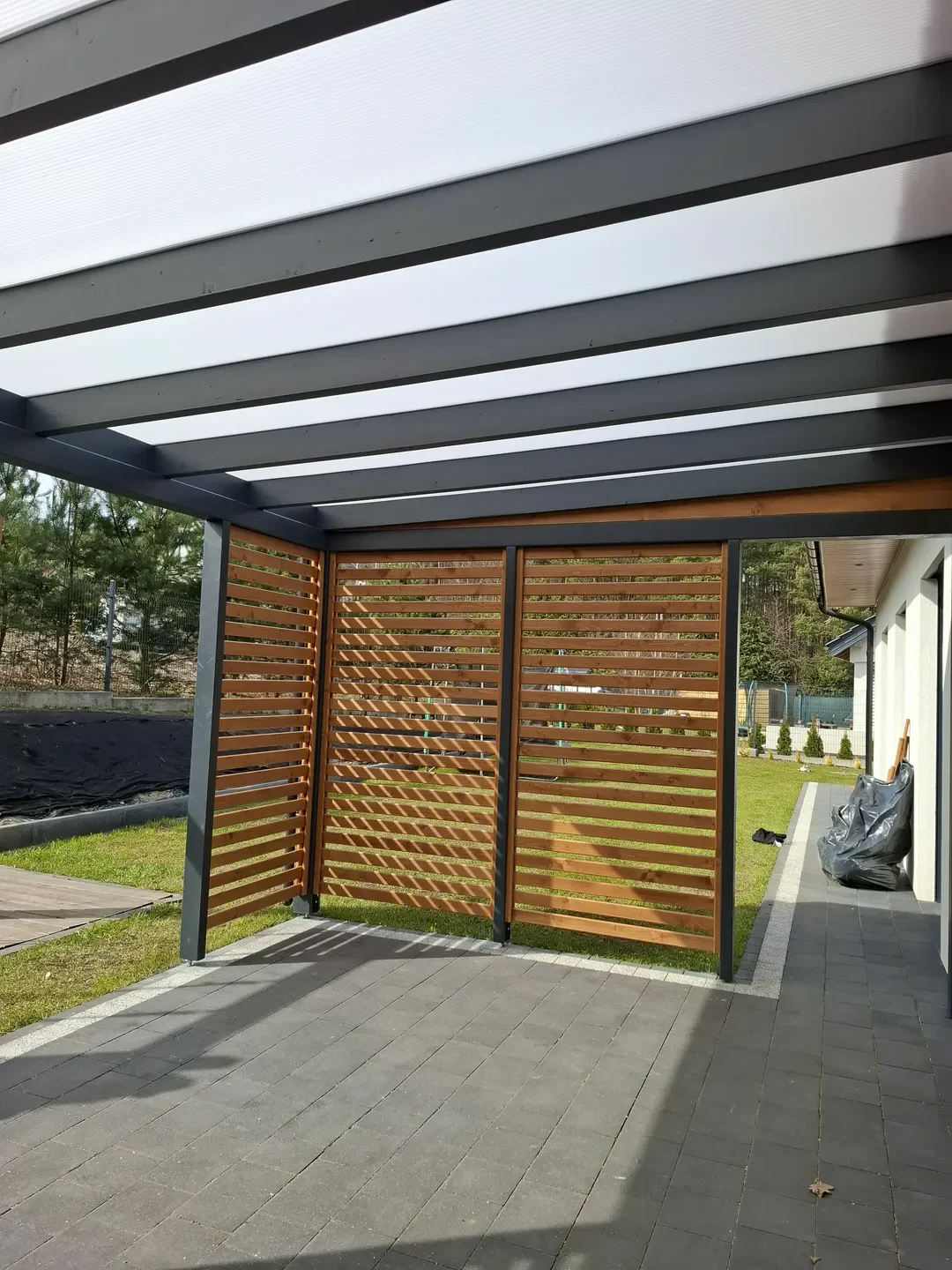 Zadaszenie tarasu z poziomymi drewnianymi osłonami bocznymi i przezroczystym dachem Zadaszenia tarasów