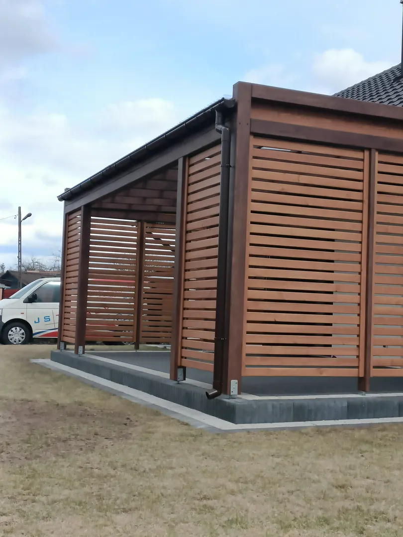 Carport z drewnianych lameli z dachem, umieszczony na betonowym fundamencie