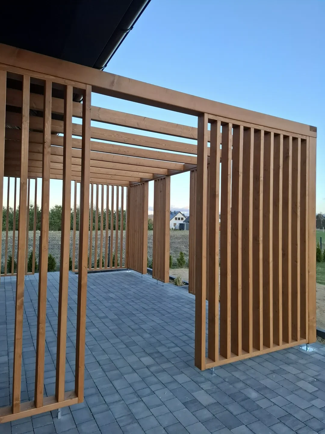 Pergole ogrodowe drewniana pergola z poziomymi i pionowymi słupkami na tarasie