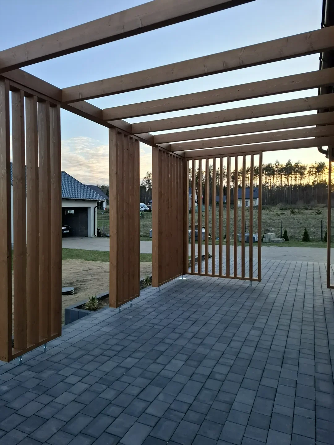 Pergole drewniane z drewnianą konstrukcją z desek i zadaszeniem nad kostką brukową