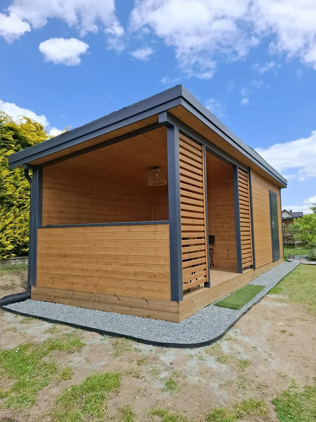 Drewniana wiata ogrodowa z metalową konstrukcją i przestronnym zadaszeniem na podłożu z żwiru