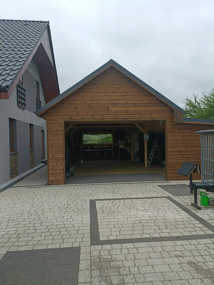 Drewniany carport z dwuspadowym dachem na kamiennym podjeździe