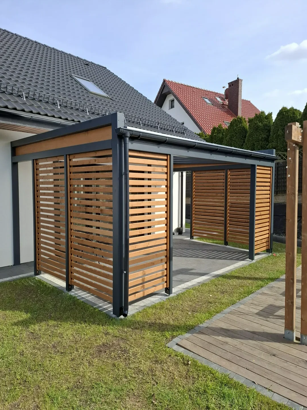 Carport z metalową konstrukcją i drewnianymi panelami bocznymi przy nowoczesnym domu