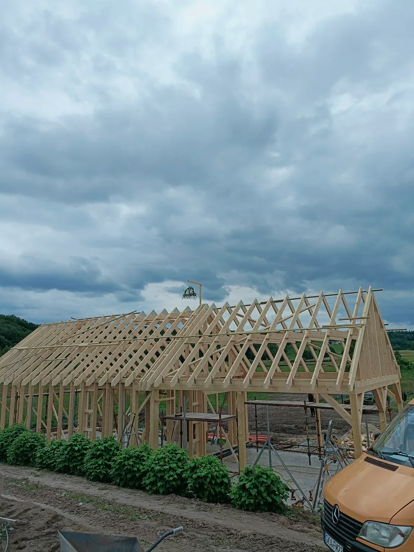 Szkieletowa konstrukcja drewnianego budynku z widocznymi krokwiami na placu budowy (Domki szkieletowe)