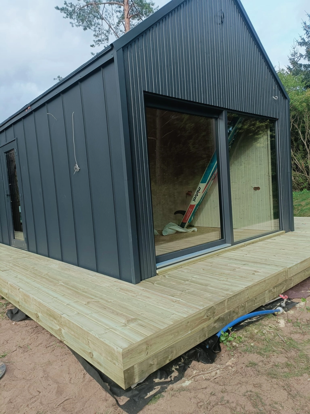 Taras drewniany z szerokich desek przy nowoczesnym obiekcie z dużym przeszkleniem