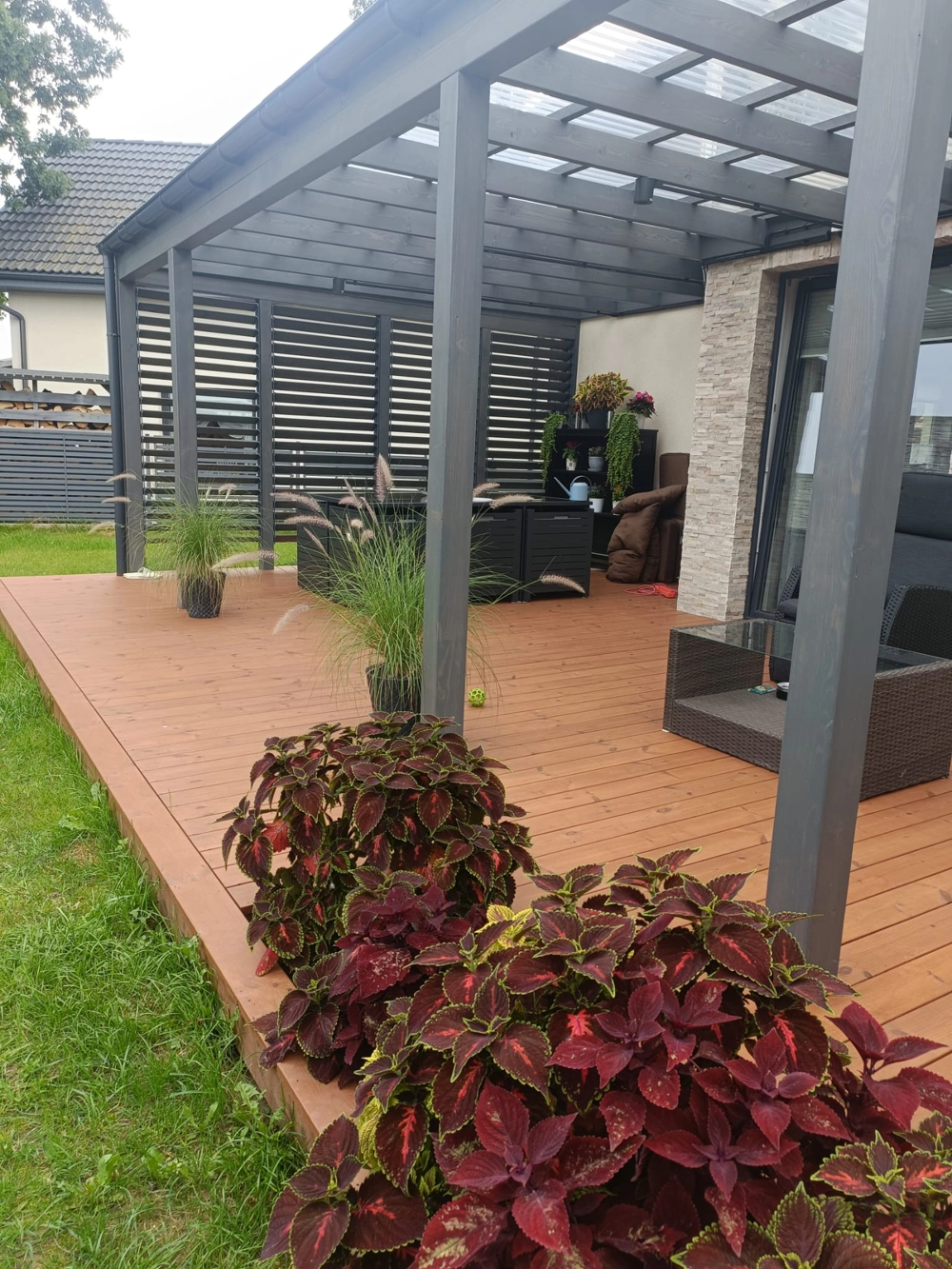 Pergole drewniane nad tarasem z kompozytową deską i roślinami