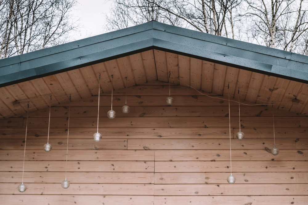 Elewacje drewniane z podbitką dachu i wiszącymi dekoracyjnymi lampami